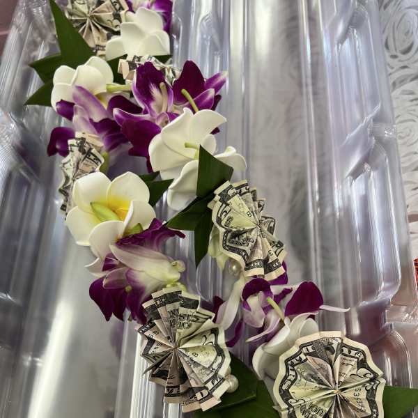 Purple and white orchid lei with folded dollar bills