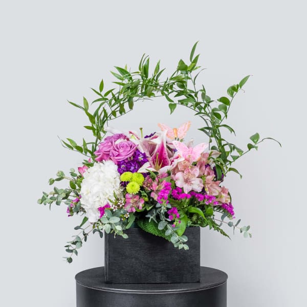 Mixed floral arrangement in a black box with pink, white, and purple blooms