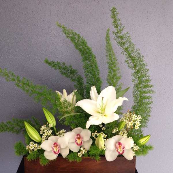 White lilies and orchids in a rectangular wooden container