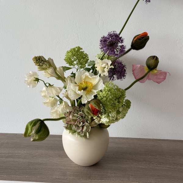 White vase arrangement with white, green, purple, and pink flowers