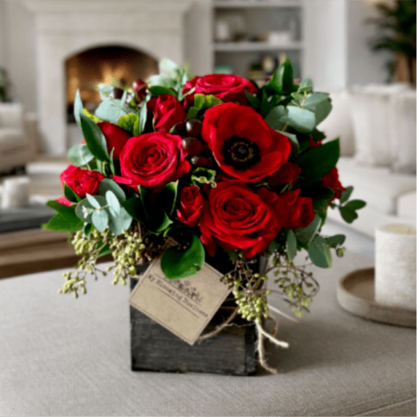 Red roses and a red anemone in a black square vase
