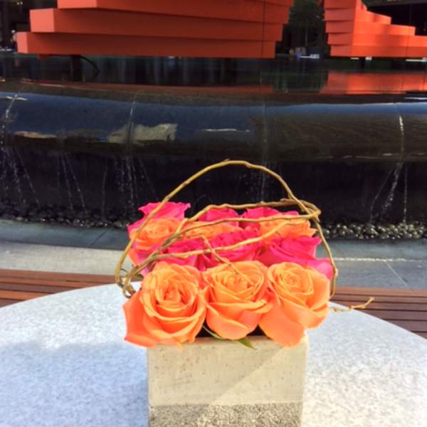 Basket of orange and pink roses with a twig handle