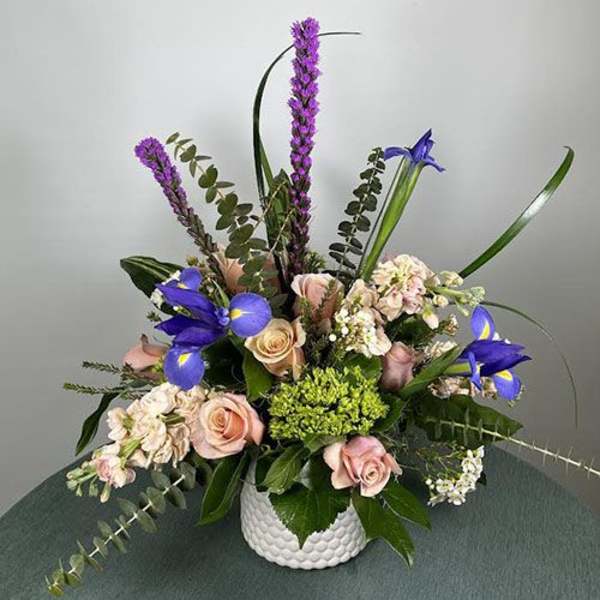 Mixed bouquet of pink roses and purple irises in a white vase