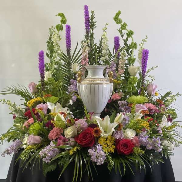 Large floral arrangement with a white urn centerpiece and mixed blooms