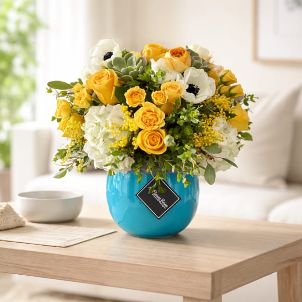 Yellow and white flower arrangement in a blue vase