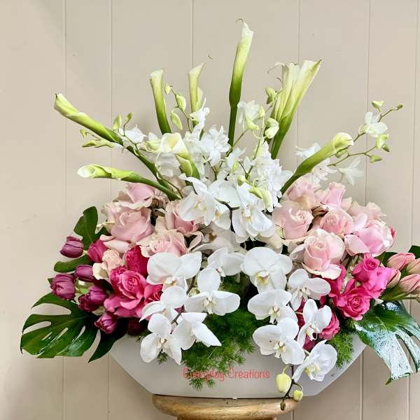Pink roses and white orchids in a white container