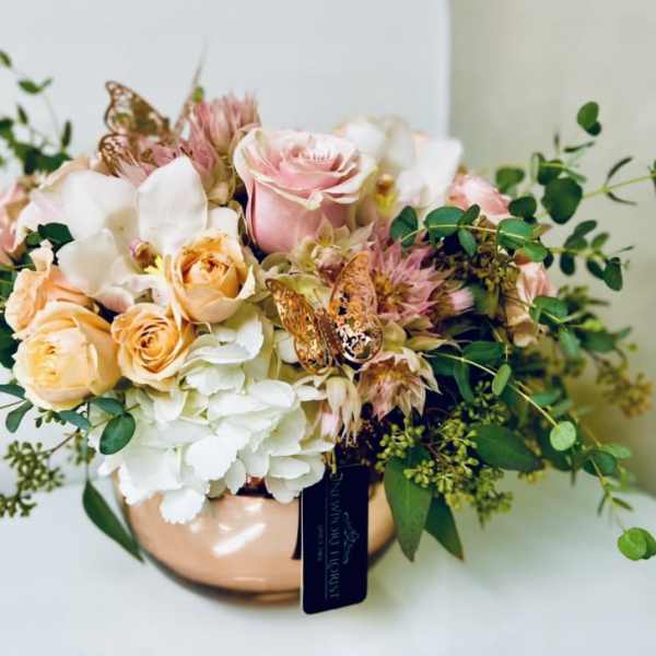 Bouquet of pink and peach roses with white hydrangeas in a copper vase