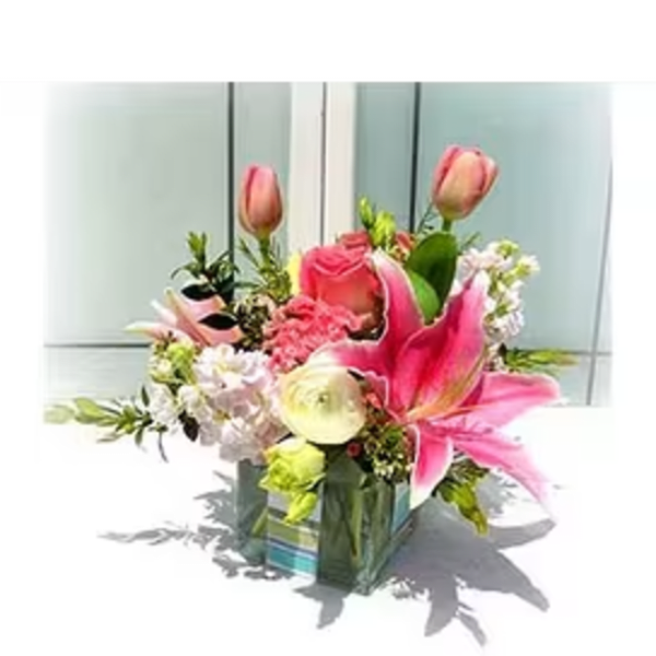 Pink lilies and roses in a glass vase with mixed blooms