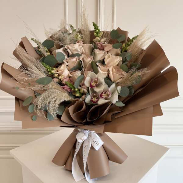 Bouquet of pale roses and orchids wrapped in brown paper