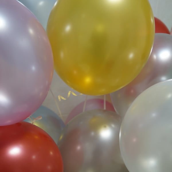 Cluster of pastel and metallic balloons in yellow, white, pink, and red tones