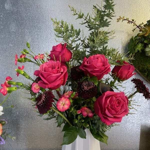 Pink roses and small accent flowers in a white vase