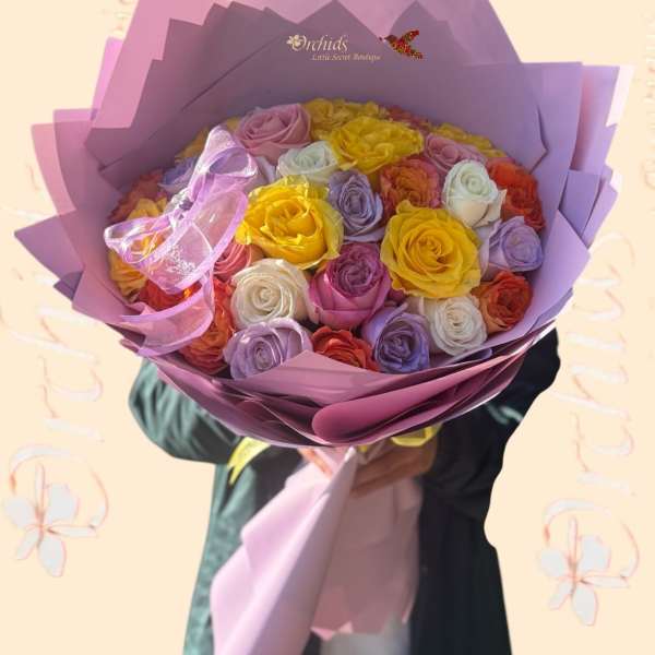 Bouquet of multicolored roses wrapped in purple paper with a pink ribbon