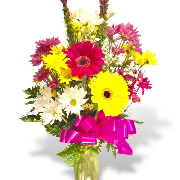 Mixed bouquet of bright daisies in a glass vase with a pink ribbon