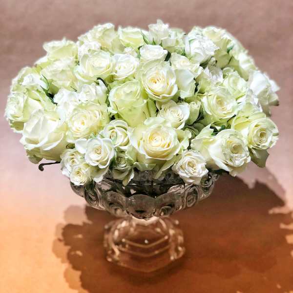 White rose bouquet in a clear glass pedestal vase