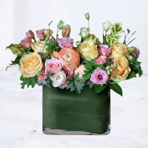Mixed pastel bouquet in a dark green square vase