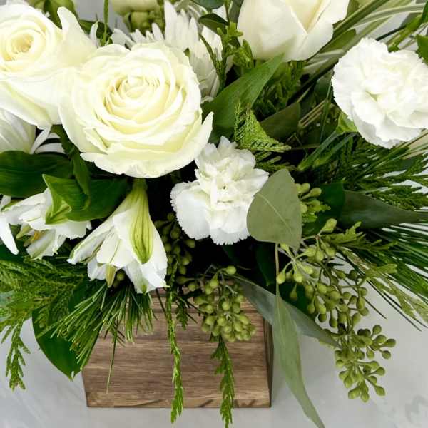 White roses and lilies in a wooden box with greenery