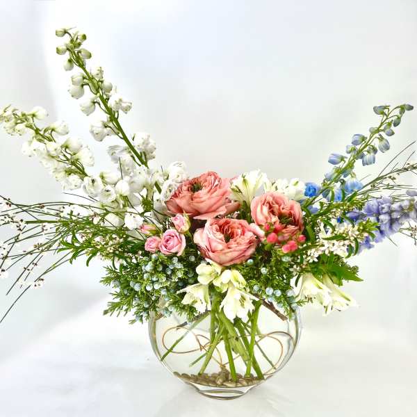 Mixed floral arrangement in a round glass vase with pink and white blooms