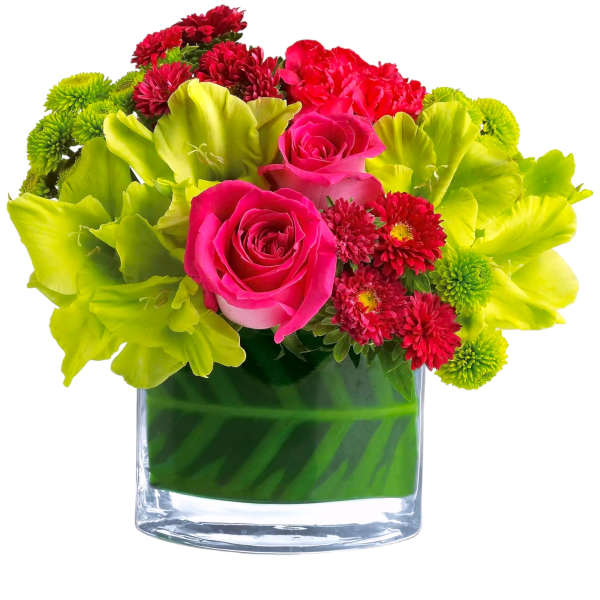 Pink roses and red flowers in a clear glass vase with bright green blooms