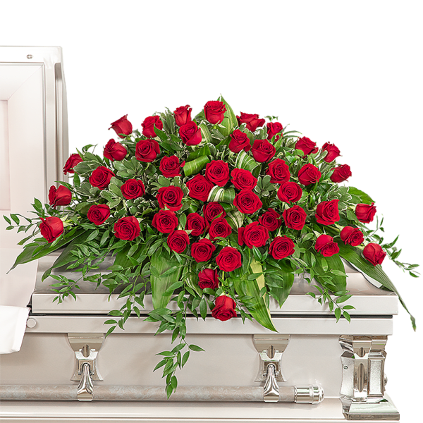 Red rose casket spray with trailing greenery on a white coffin