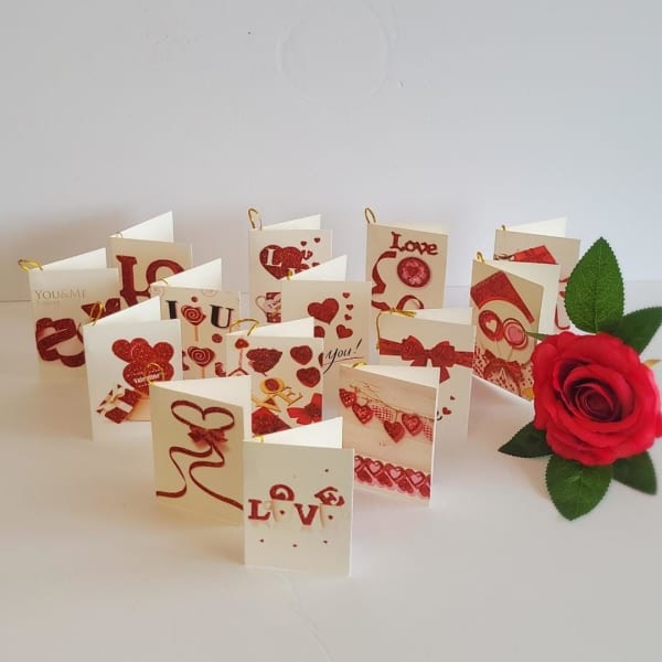 Red rose beside a spread of Valentine-themed greeting cards