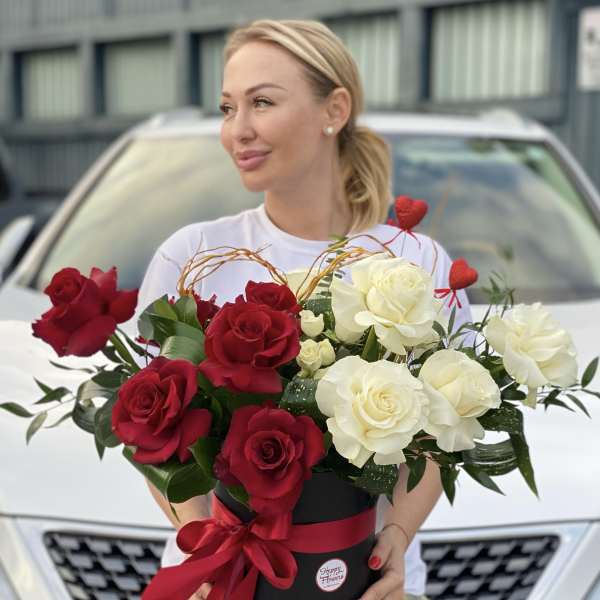 Red and white roses in a black hatbox with a red ribbon