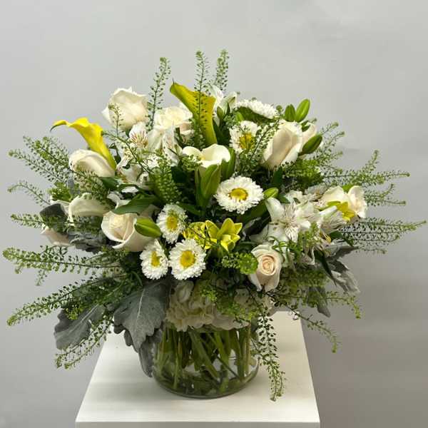 White and yellow floral arrangement in a glass vase