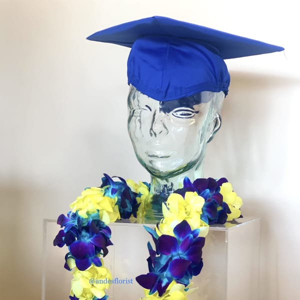 Graduation display with a blue cap and a lei of yellow and purple flowers