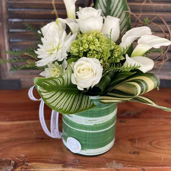 White roses and calla lilies arranged in a green striped container