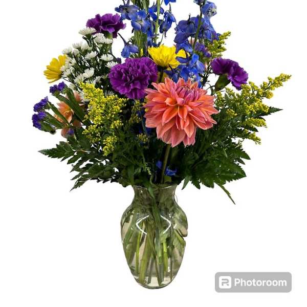 Mixed bouquet in a clear glass vase with blue, purple, yellow, and peach flowers