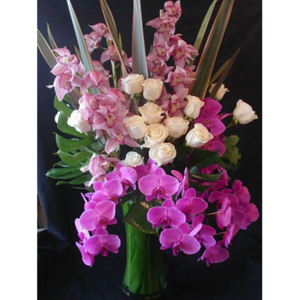 Pink orchids and cream roses in a tall glass vase