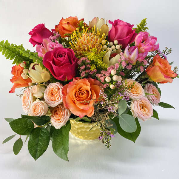 Mixed bouquet of roses and tropical blooms in a yellow vase