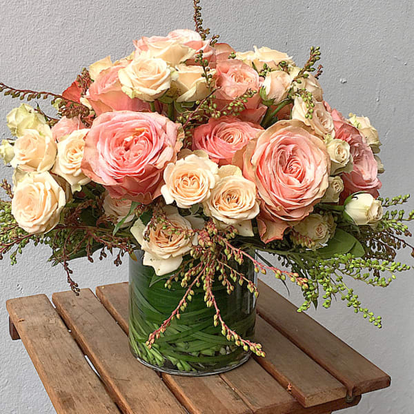 Pink and cream roses arranged in a glass vase