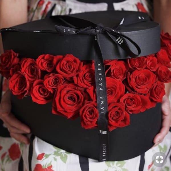 Black hatbox filled with red roses and tied with a black ribbon