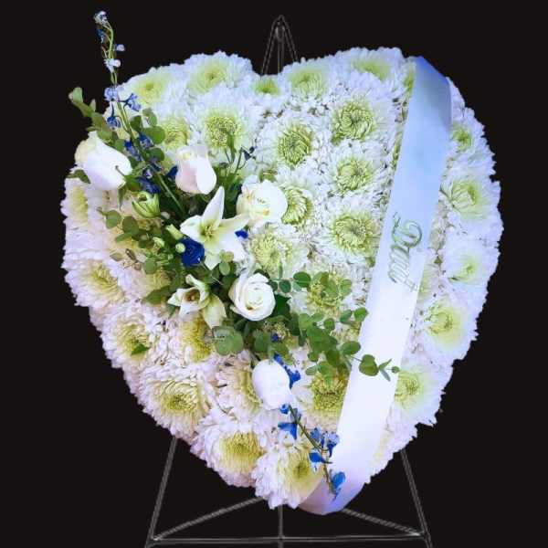 Heart-shaped white floral funeral tribute with a white ribbon