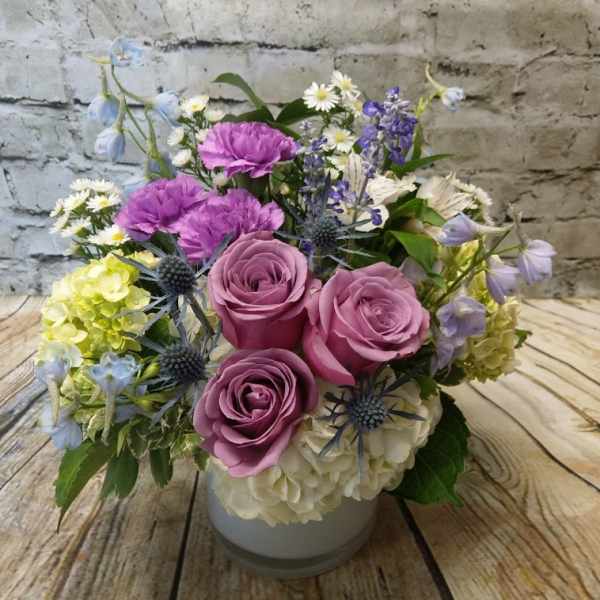 Pink roses and purple flowers arranged in a white vase