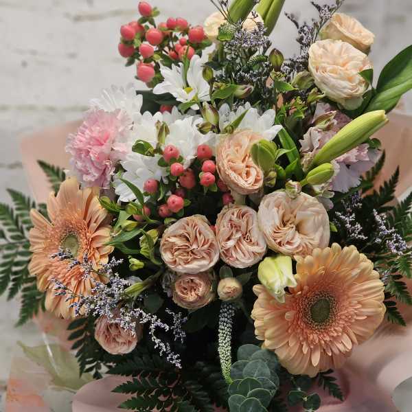 Bouquet of peach roses, gerbera daisies, and white daisies with pink berries