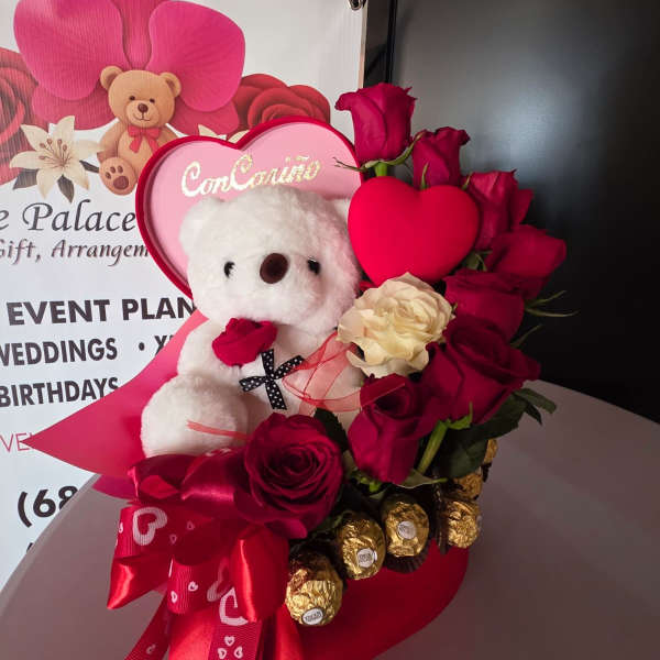 Heart-shaped rose arrangement with a teddy bear and chocolates