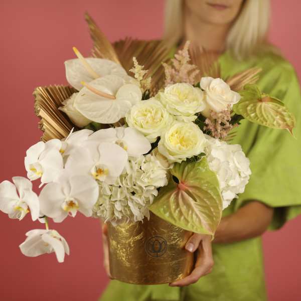 White orchid and rose arrangement in a gold container