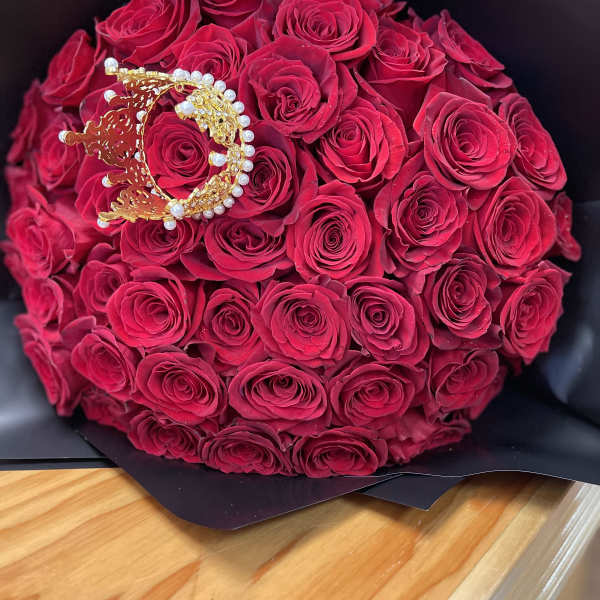 Bouquet of deep pink roses wrapped in black paper with a jeweled crown accent