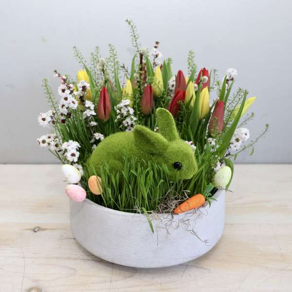 Spring arrangement with tulips and a moss bunny in a round planter