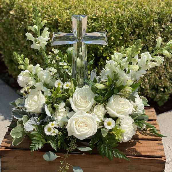 White floral arrangement with a clear cross centerpiece in a wooden box