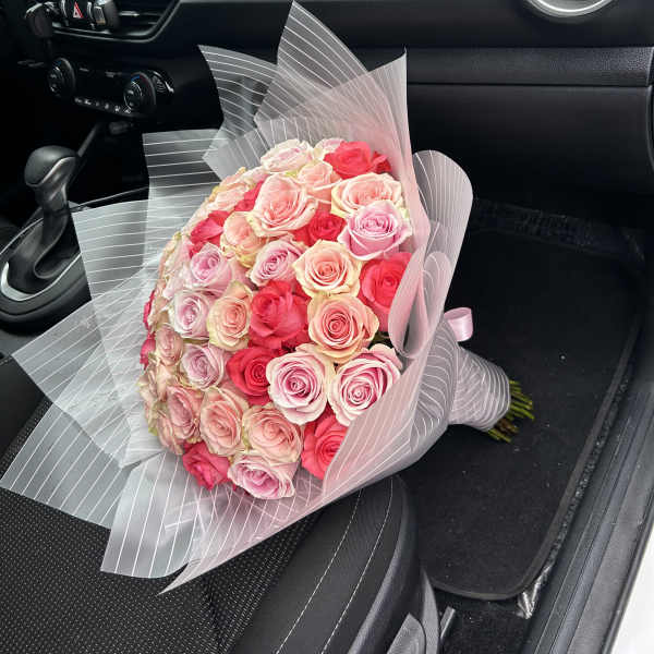 Bouquet of pink and red roses wrapped in translucent striped paper