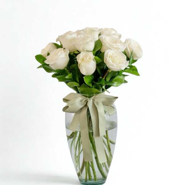 White roses in a clear glass vase with a ribbon bow