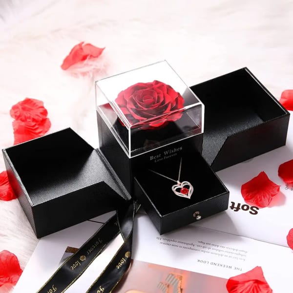 Black gift box with a red rose under a clear lid and a heart necklace inside