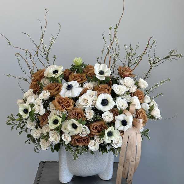 Large bouquet of white and brown roses with white anemones in a gray vase