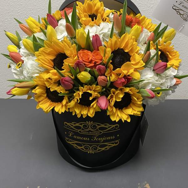 Bouquet of sunflowers, tulips, and white hydrangeas in a black hat box