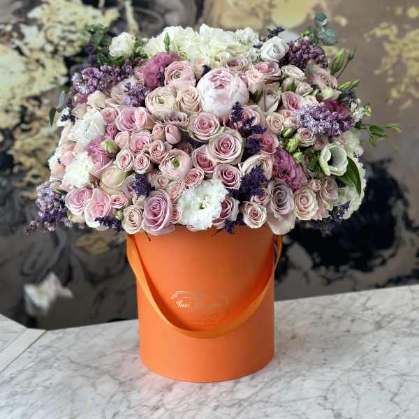 Large bouquet of pink and white roses in an orange hatbox