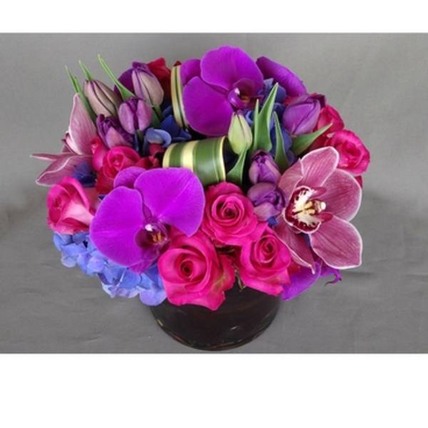 Bouquet of pink roses, purple orchids, and blue hydrangeas in a black vase