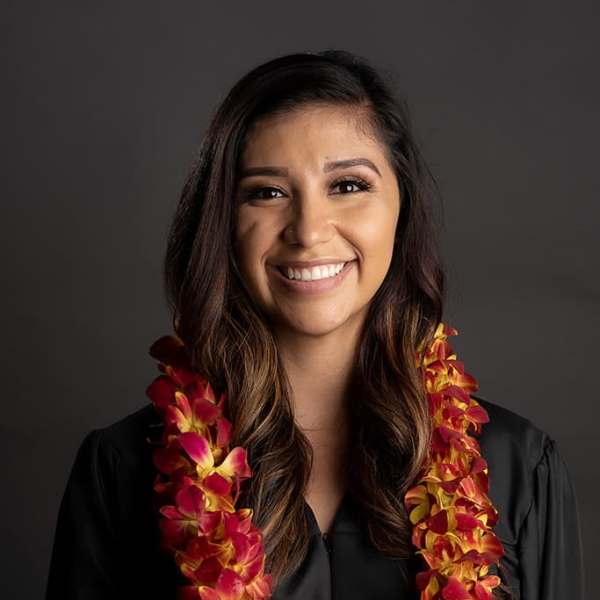 Woman wearing a red and yellow orchid lei over a black gown