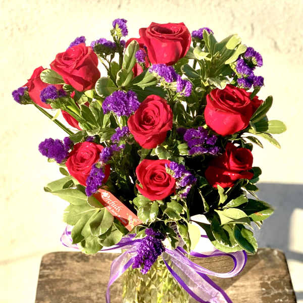 Bouquet of red roses and purple filler flowers in a glass vase